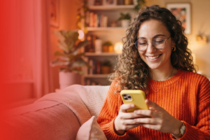 Renová tu celular 5G con Claro Costa Rica Mujer sonriente usando su celular nuevo en casa tras renovar su equipo 5G con Claro Costa Rica